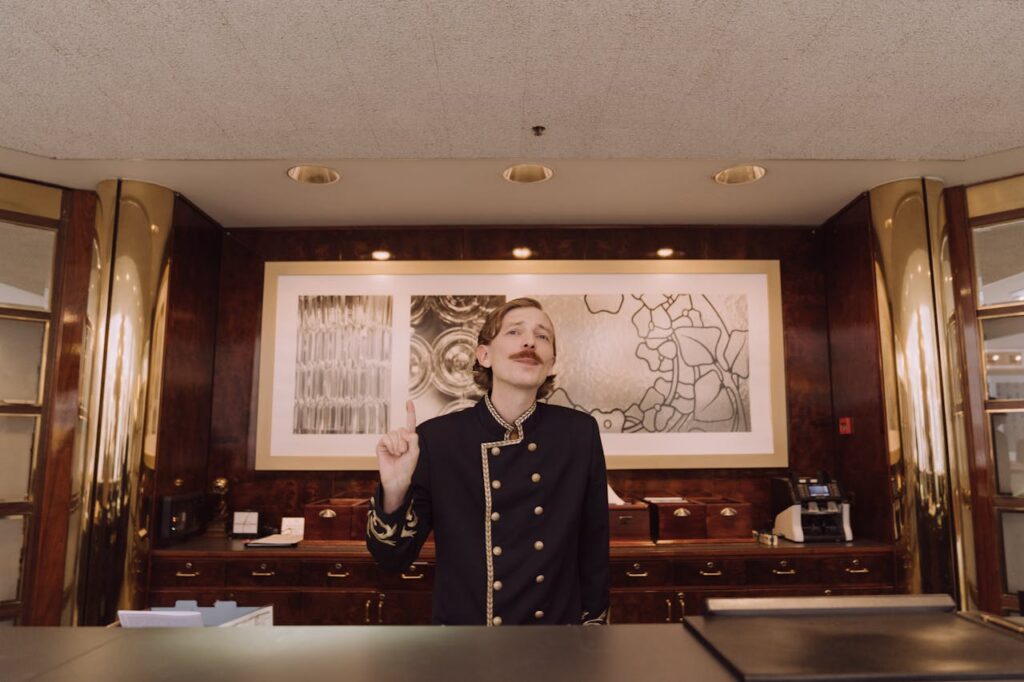 The Art of Drawing Readers In: Your attractive post title goes here A luxury hotel receptionist in uniform stands behind the opulent front desk, ready to assist guests.
